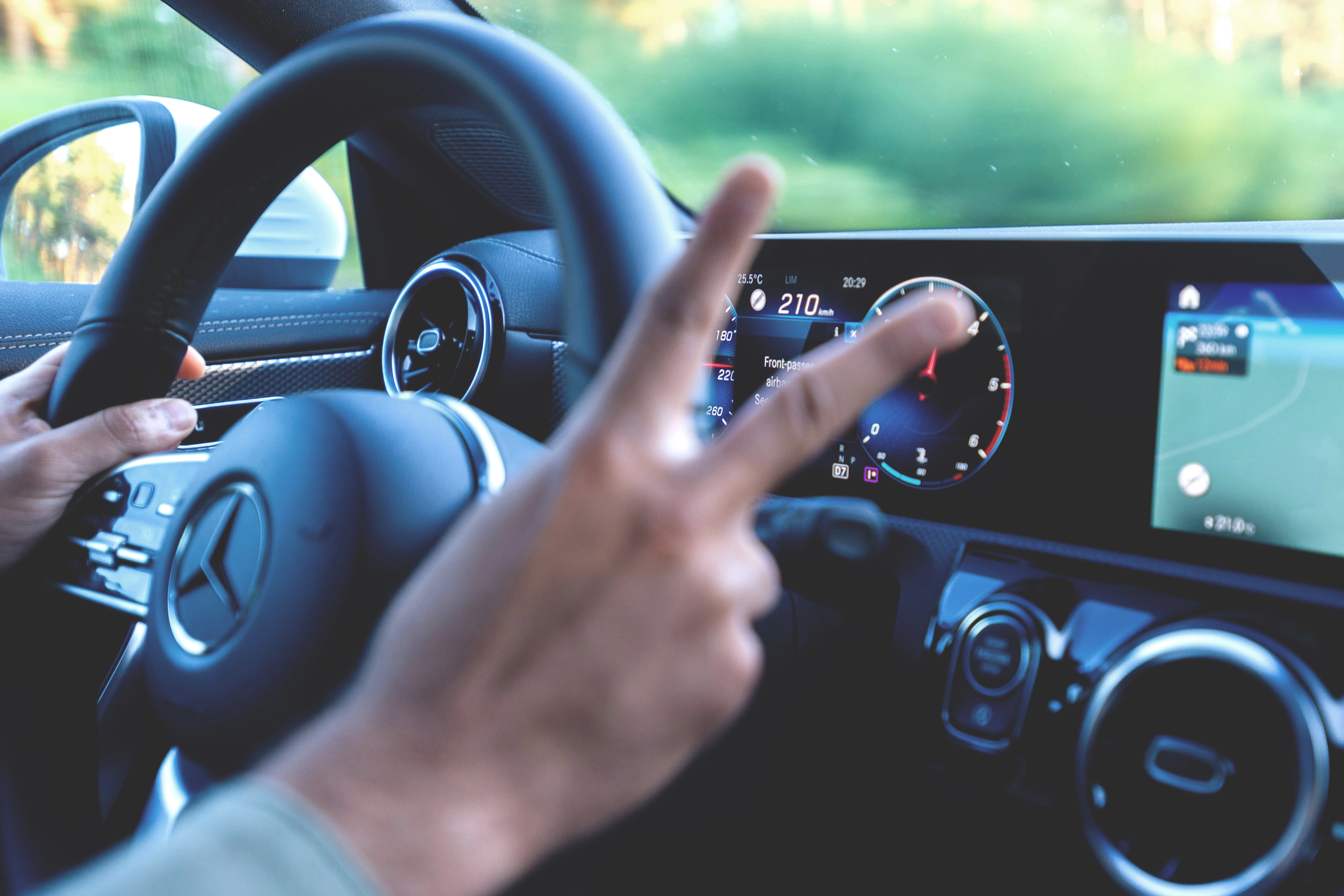 image des mains d'une personne au volant d'une voiture qui fait le signe du paix